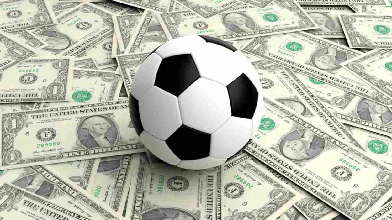 Bola de futebol sobre diversas notas de dólar.