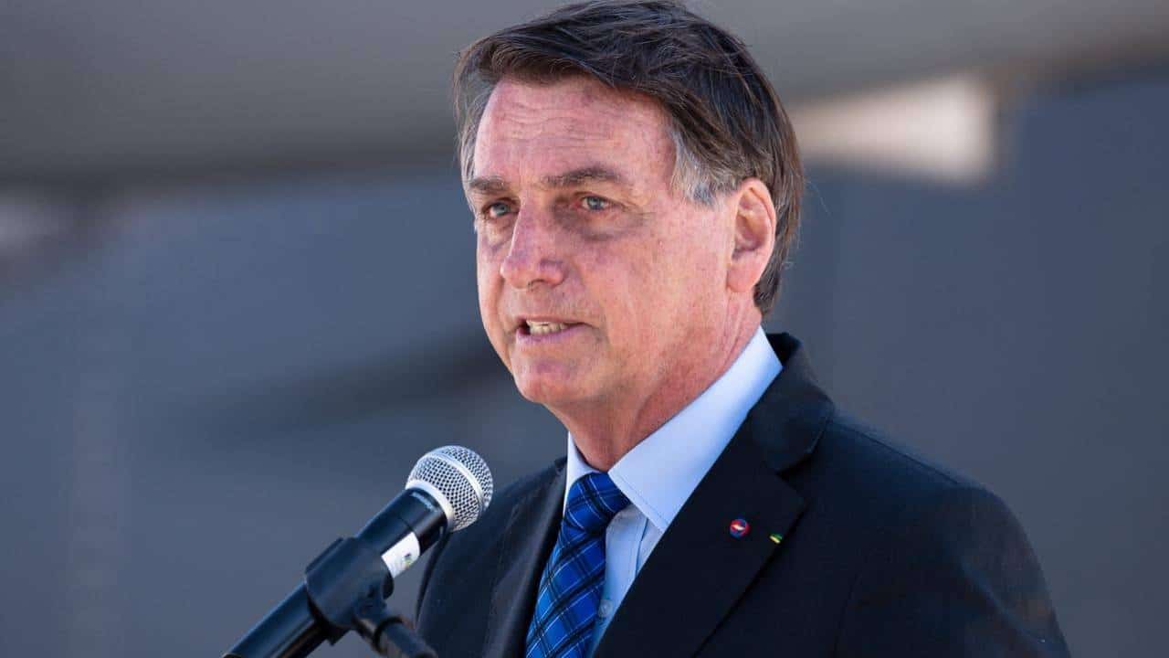 Imagem do ex-presidente Jair Messias Bolsonaro em frente a um microfone, discursando.
