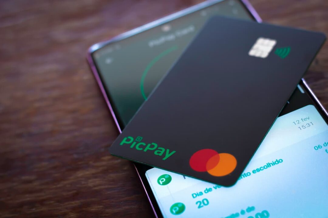 A imagem mostra um cartão de crédito picpay em cima de um celular, aberto no aplicativo.