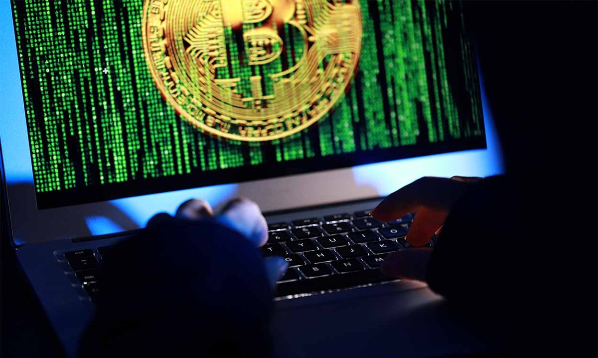 Tela de um notebook com a imagem de um bitcoin coberto com código binário criptomoedas
