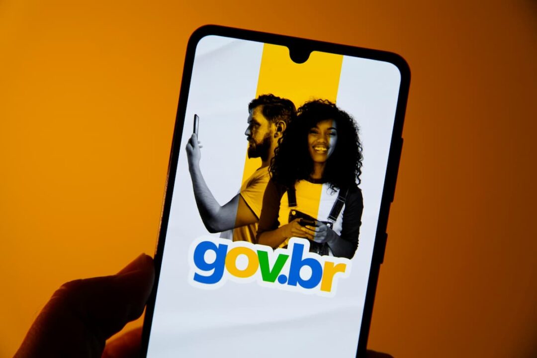 A imagem mostra uma mão segurando um celular com a tela aberta no app Gov.br