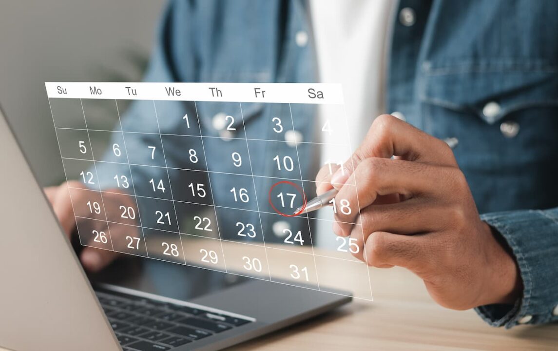 laptop e mão circulando sexta-feira em calendário