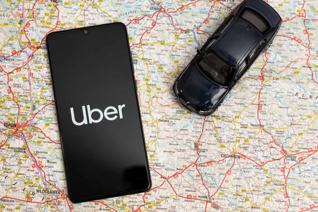 mapa, celular com aplicativo Uber e miniatura de carro
