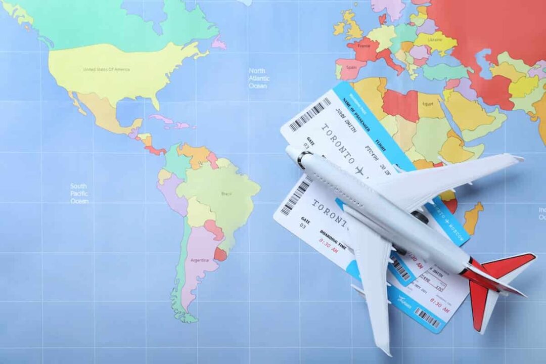 Imagem de um mapa mundi com passagens aéreas para viajar para o México ou Canadá e um avião de brinquedo em cima.