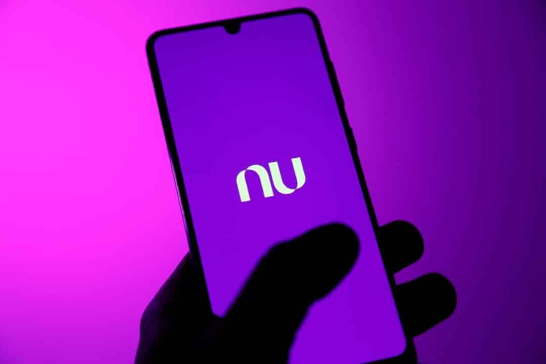 mão segurando celular com logo do Nubank na tela