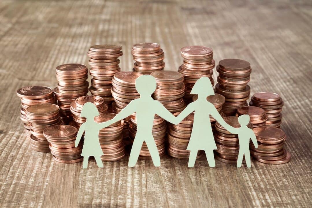 Bonecos de papel representando uma família em frente a várias pilhas de moedas.