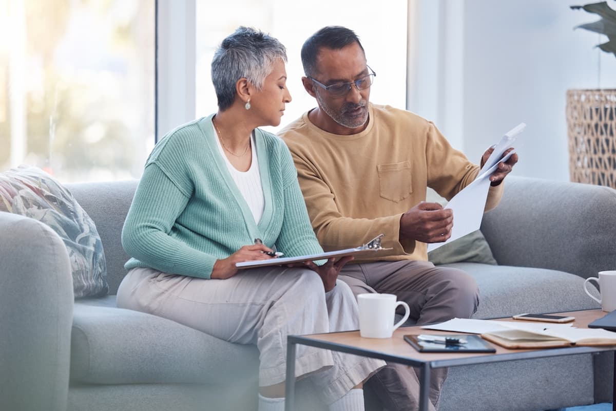 Imagem de um senhor e uma senhora olhando para papéis da aposentadoria e fazendo contas em relação ao auxílio.
