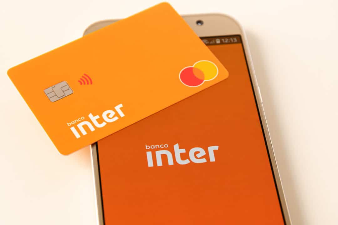 Na imagem, celular com aplicativo do banco Inter na tela inicial e cartão da instituição sobre a tela.