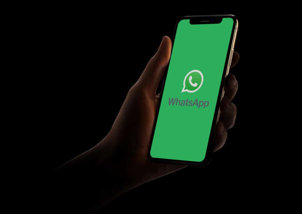 Mão segurando celular com o WhatsApp sendo iniciado.