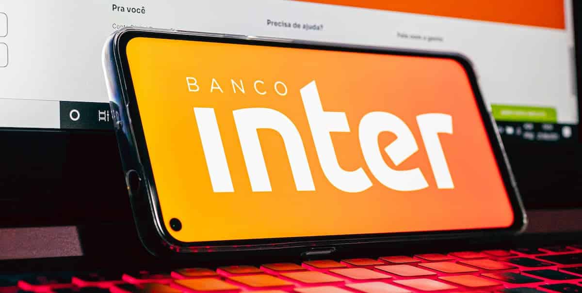 Aplicativo Banco Inter em smartphone apoiado sobre notebook