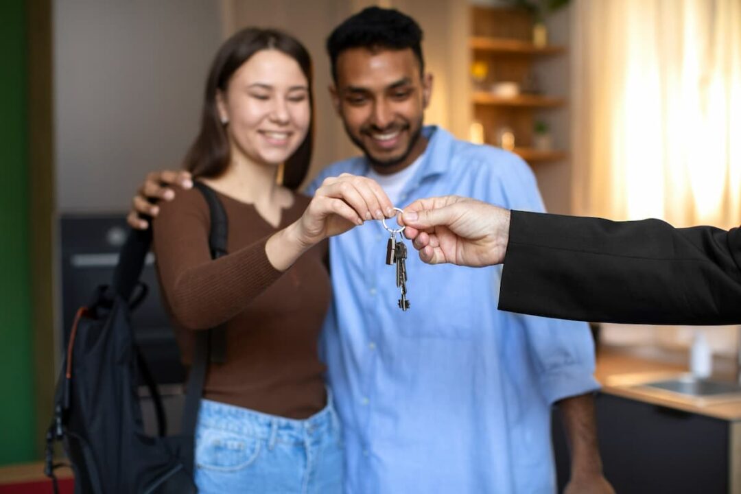 A imagem mostra um casal recebendo chaves de um imóvel.