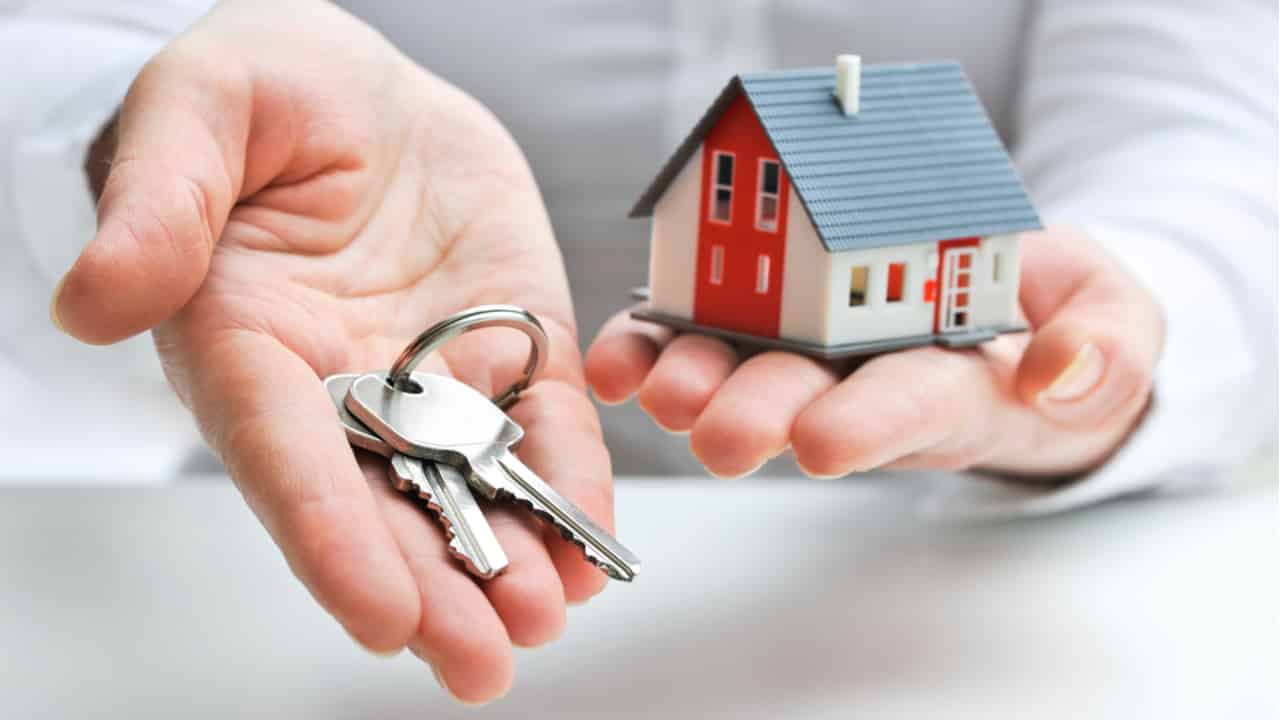 Pessoa acaba de comprar casa e está segurando uma chave a miniatura do imóvel
