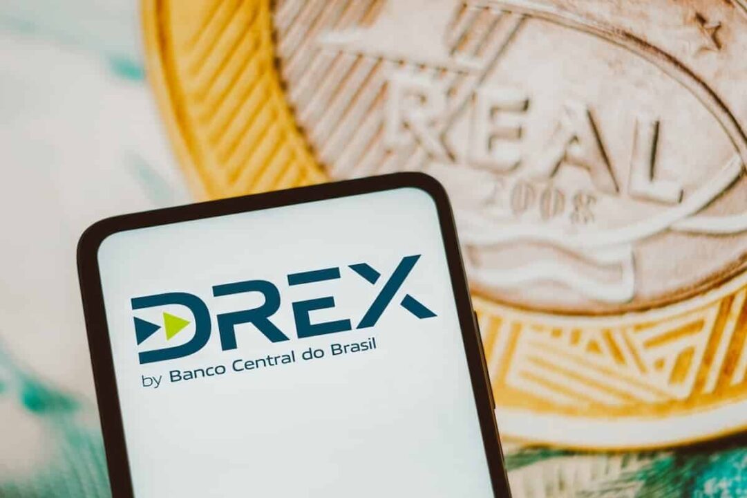 Imagem do logo do Drex, o Real Digital, com uma moeda de 1 real atrás