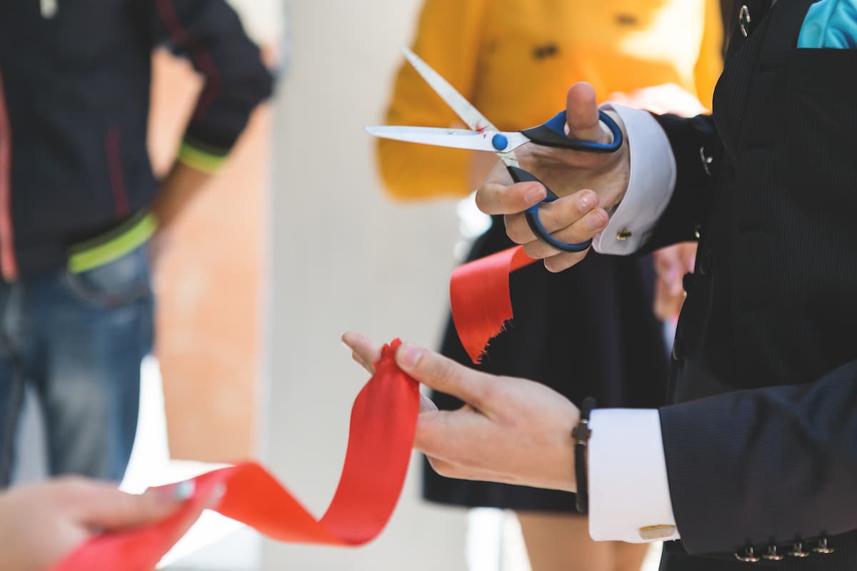 Pessoa cortando uma fita vermelha de inauguração de uma loja, simbolizando a Naterial, nova marca internacional que chegou ao Brasil.