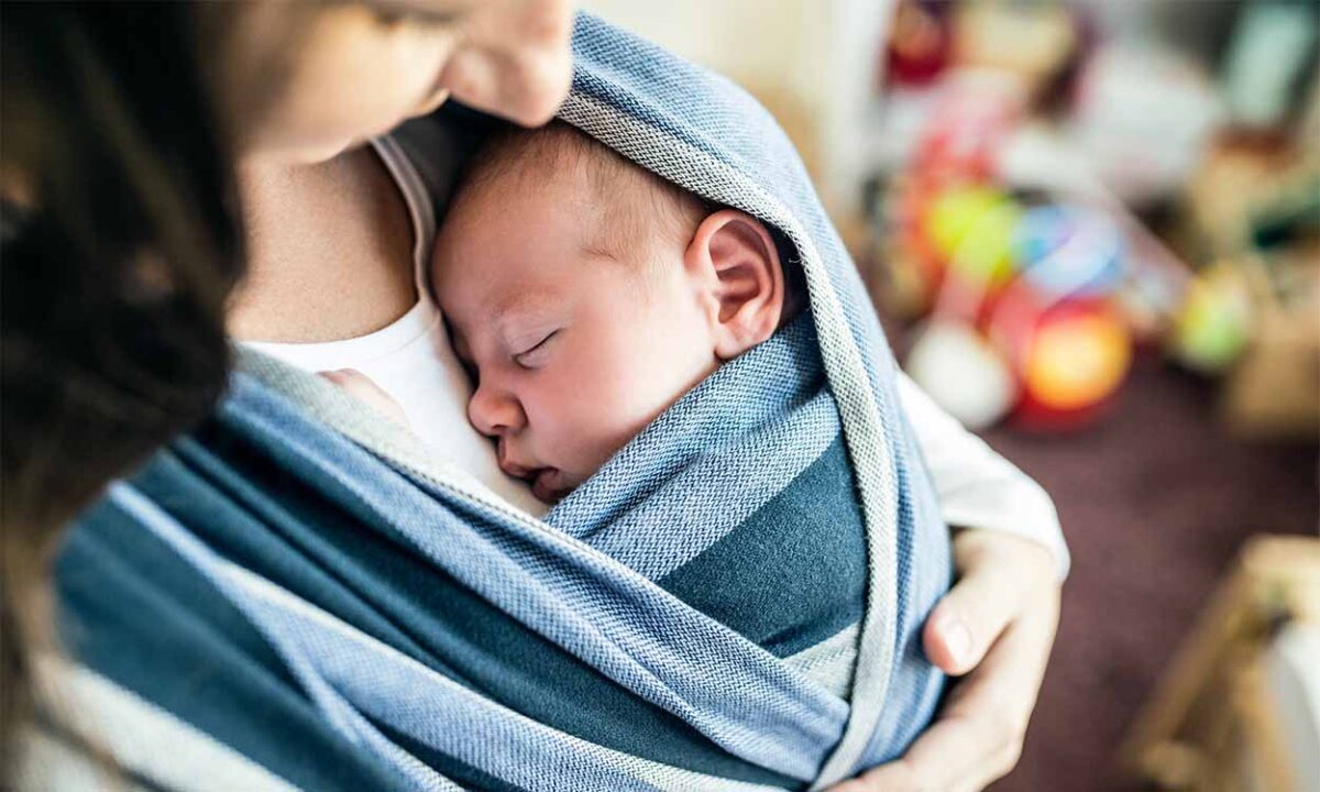 A imagem mostra uma mulher segurando e olhando um bebê.