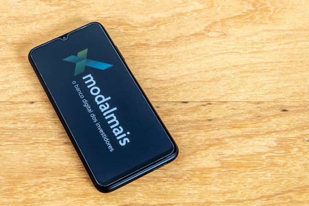 Celular com logo do modalmais em cima de uma madeira.