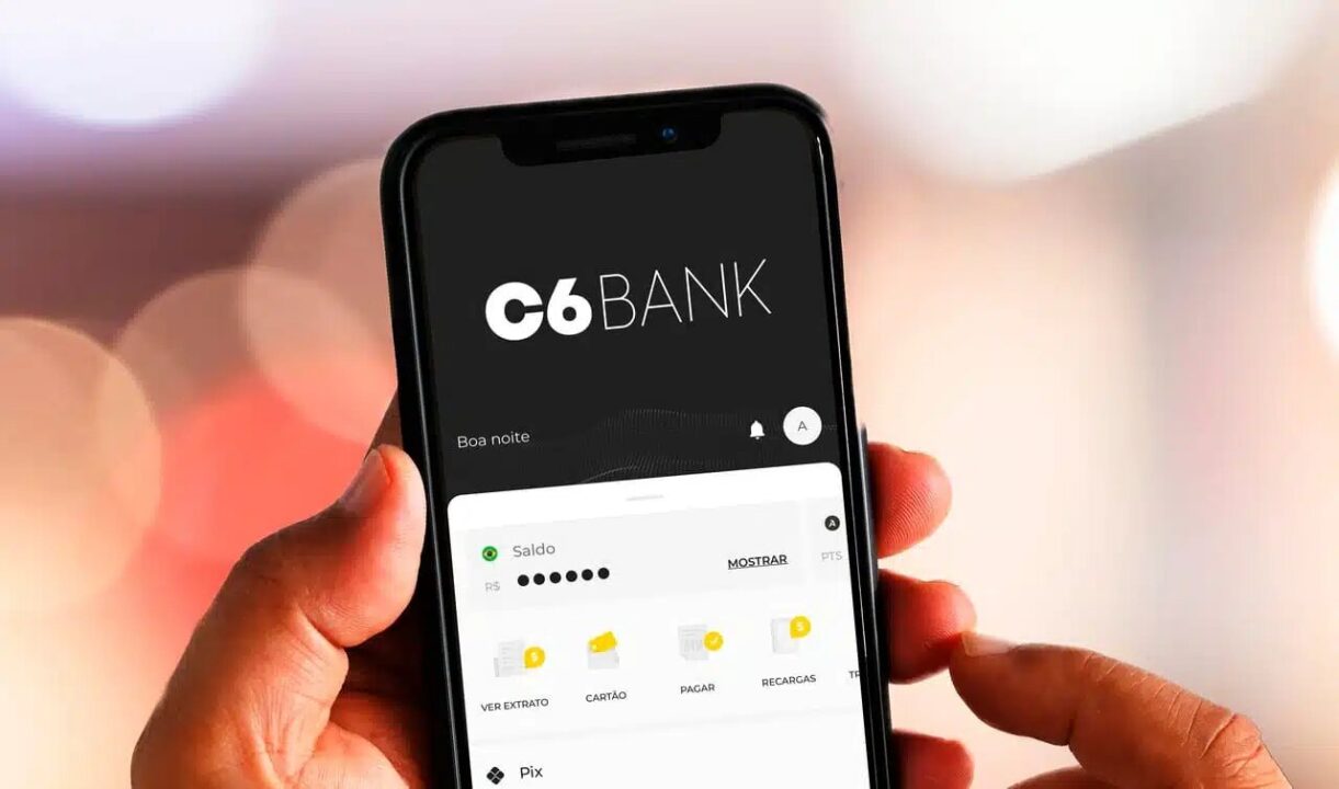 Mão segurando celular com o aplicativo do banco C6 aberto, esperando pontos.