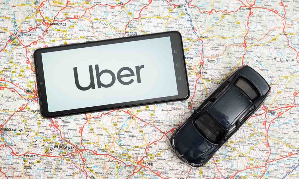 Miniatura de carro e celular com logo do uber em cima de um mapa