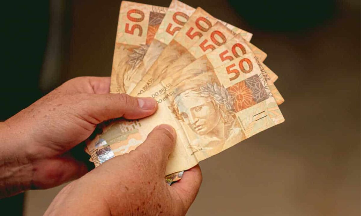 Pessoa segurando várias notas de R$ 50 do auxílio para brasileiros de R$ 300