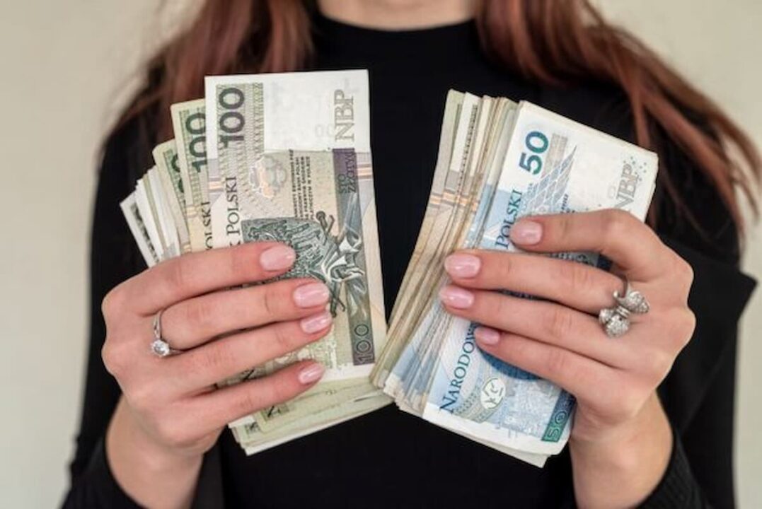 Mãos femininas segurando muitas notas de dinheiro.