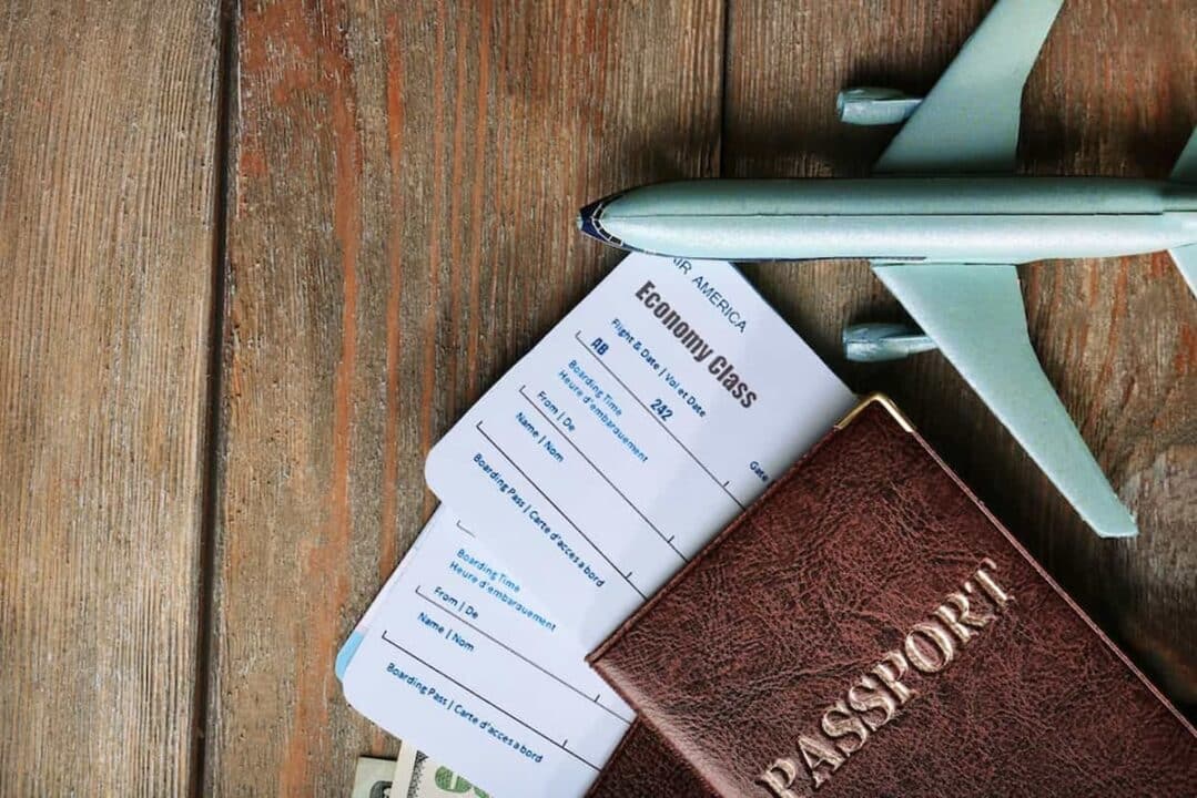 Passagem aérea em uma mesa, com passaporte e um avião de brinquedo.