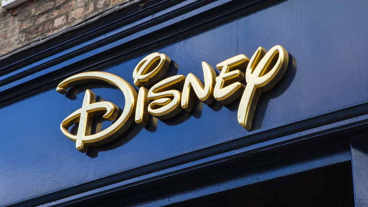 Fachada da empresa Disney em letreiro dourado sobre fundo azul.