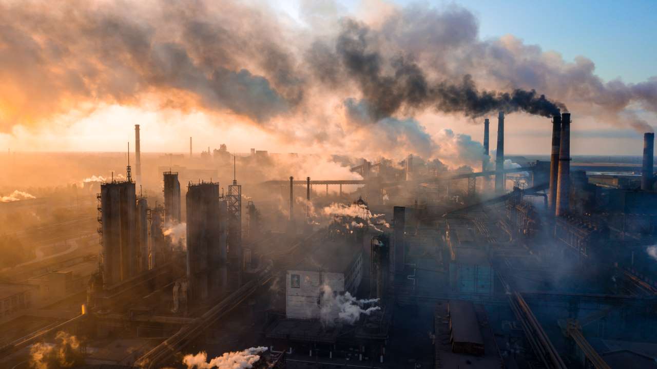 imagem de cidade com péssima qualidade do ar, com vários prédios e muita fumaça saindo de chaminés