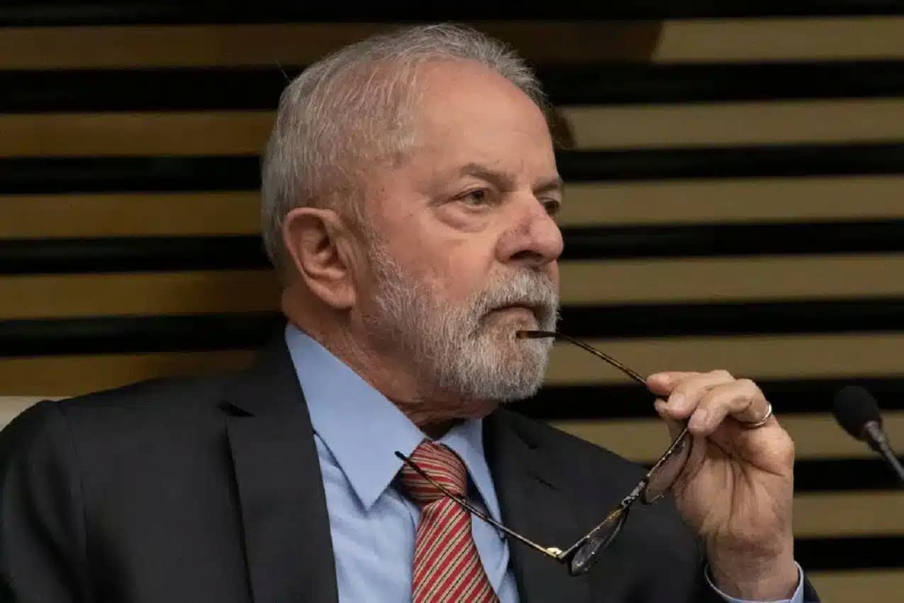 Presidente Lula com uma das hastes dos seus óculos próxima ao lábio inferior.