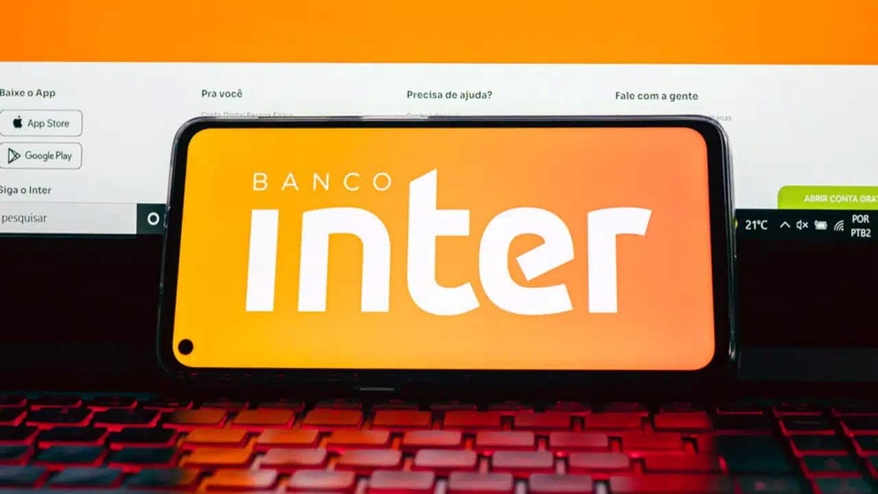 Logo do Inter na tela de um celular encostado em um notebook.