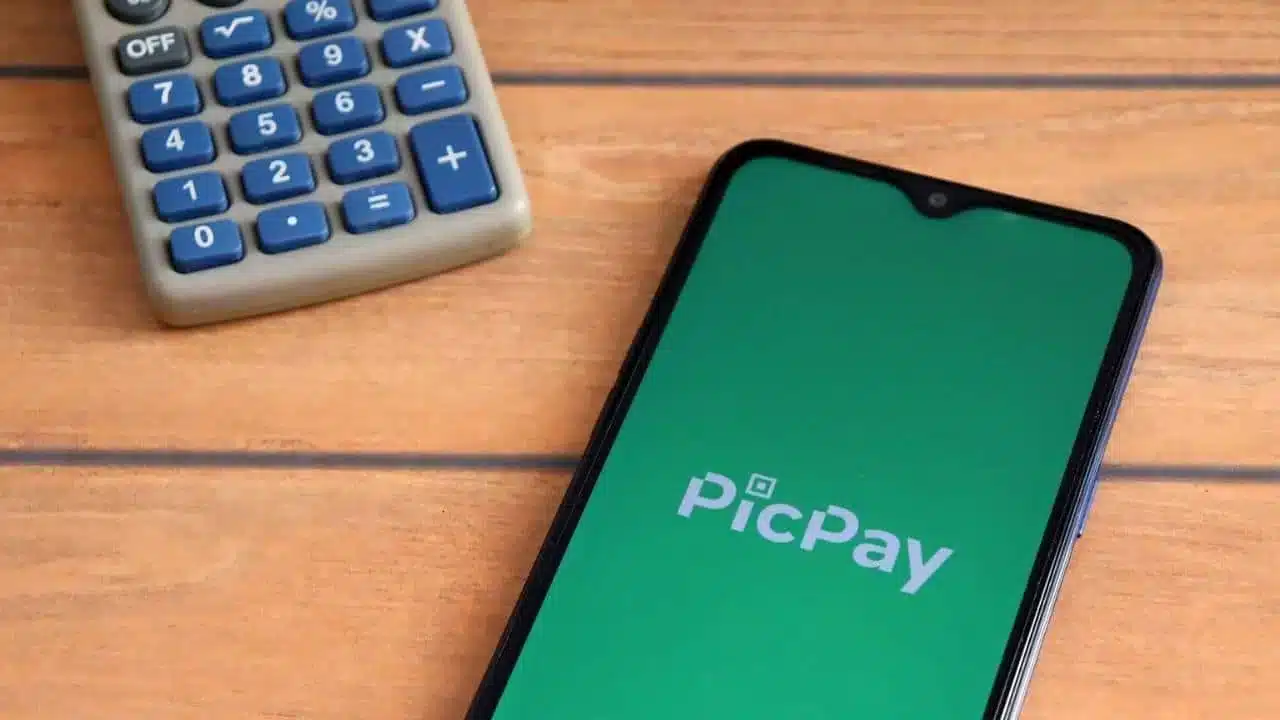 Celular com a tela inicial do app PicPay aberta ao lado de calculadora