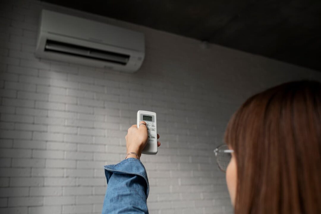 Mulher ajustando a temperatura do ar-condicionado.
