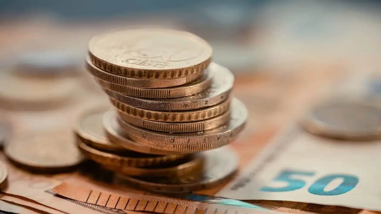 Pilha de moedas sob dinheiro em cédula