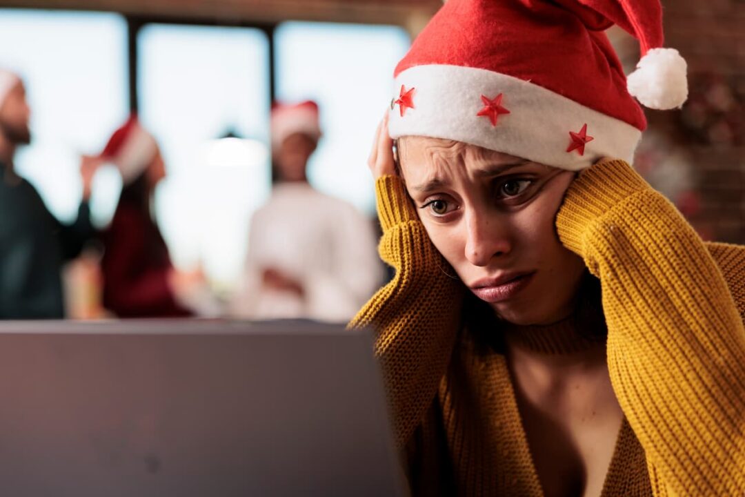 Mulher branca com gorro do Papai Noel com cara de triste trabalhando no Natal