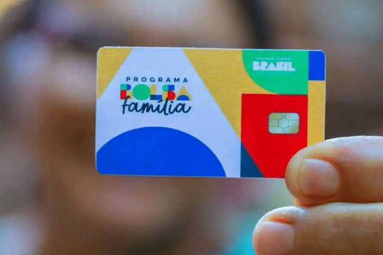 Mão segurando cartão do Bolsa Família com as cores branco, amarelo, vermelho e azul Caixa