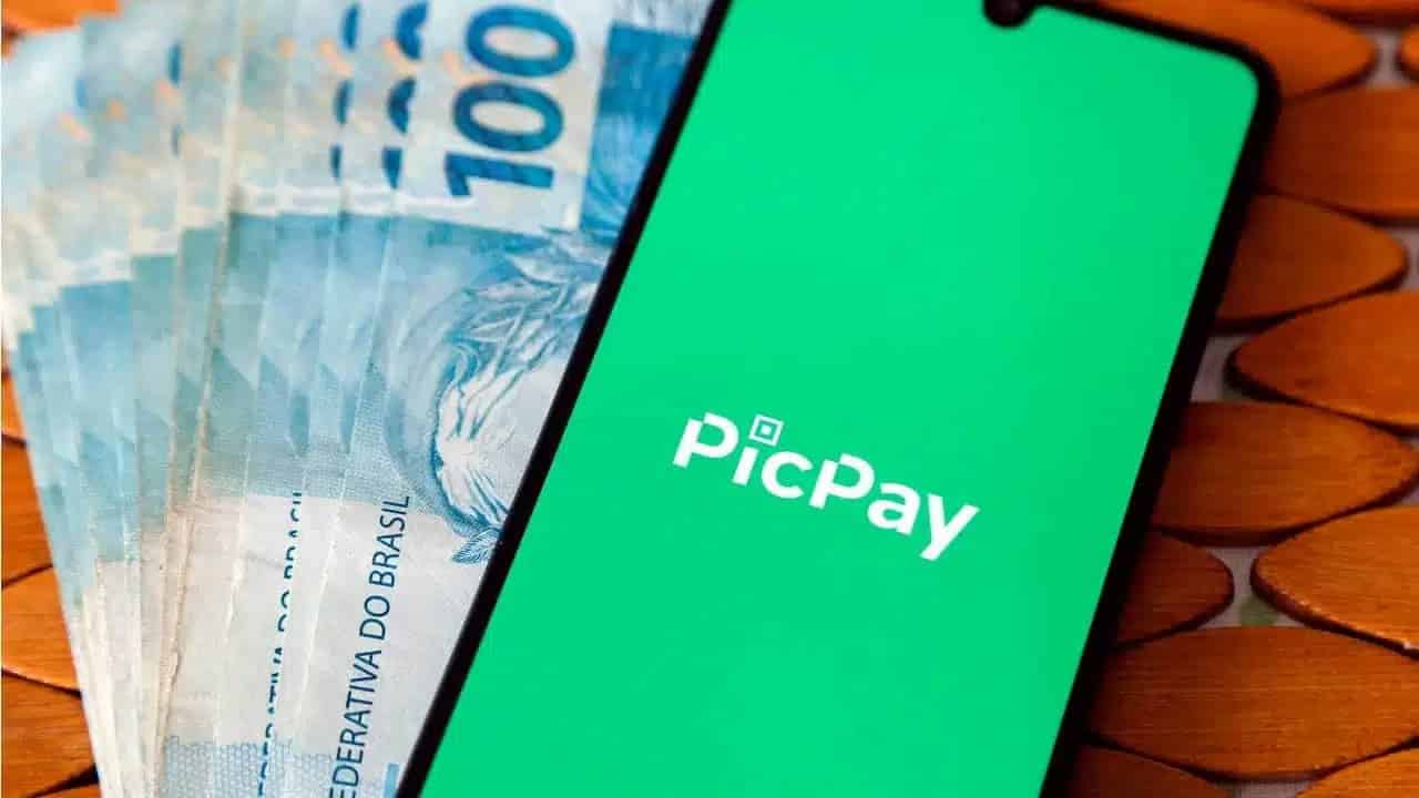 Notas de 100 reais e celular com PicPay aberto