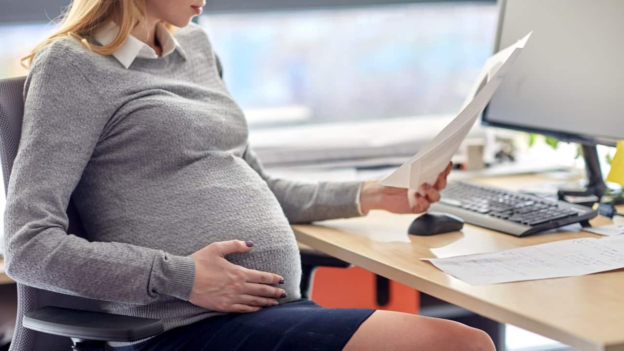Imagem de uma profissional grávida enquanto trabalha em escritório