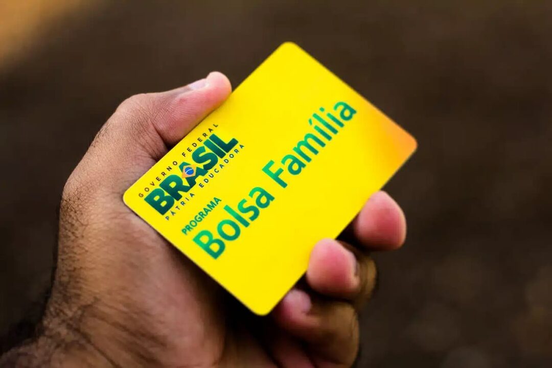Mão segurando o cartão do Bolsa Família