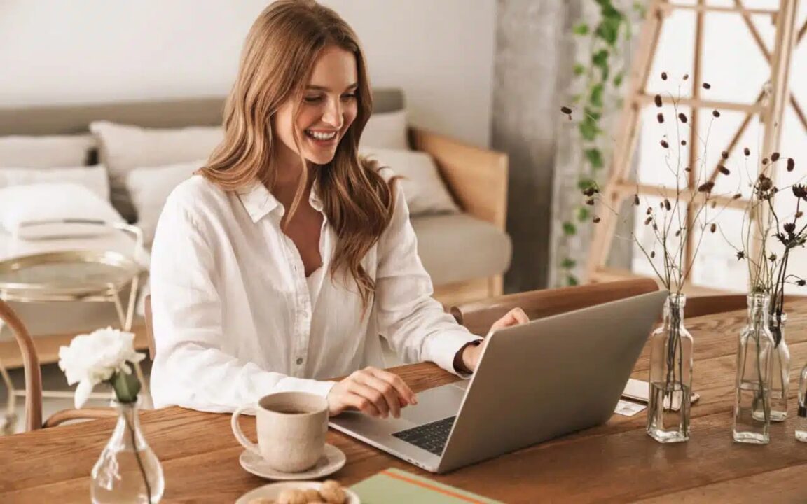 Mulher sentada em frente computador trabalhando e sorrindo profissões