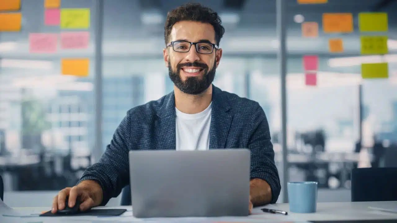 Homem sentado em frente ao computador sorrindo