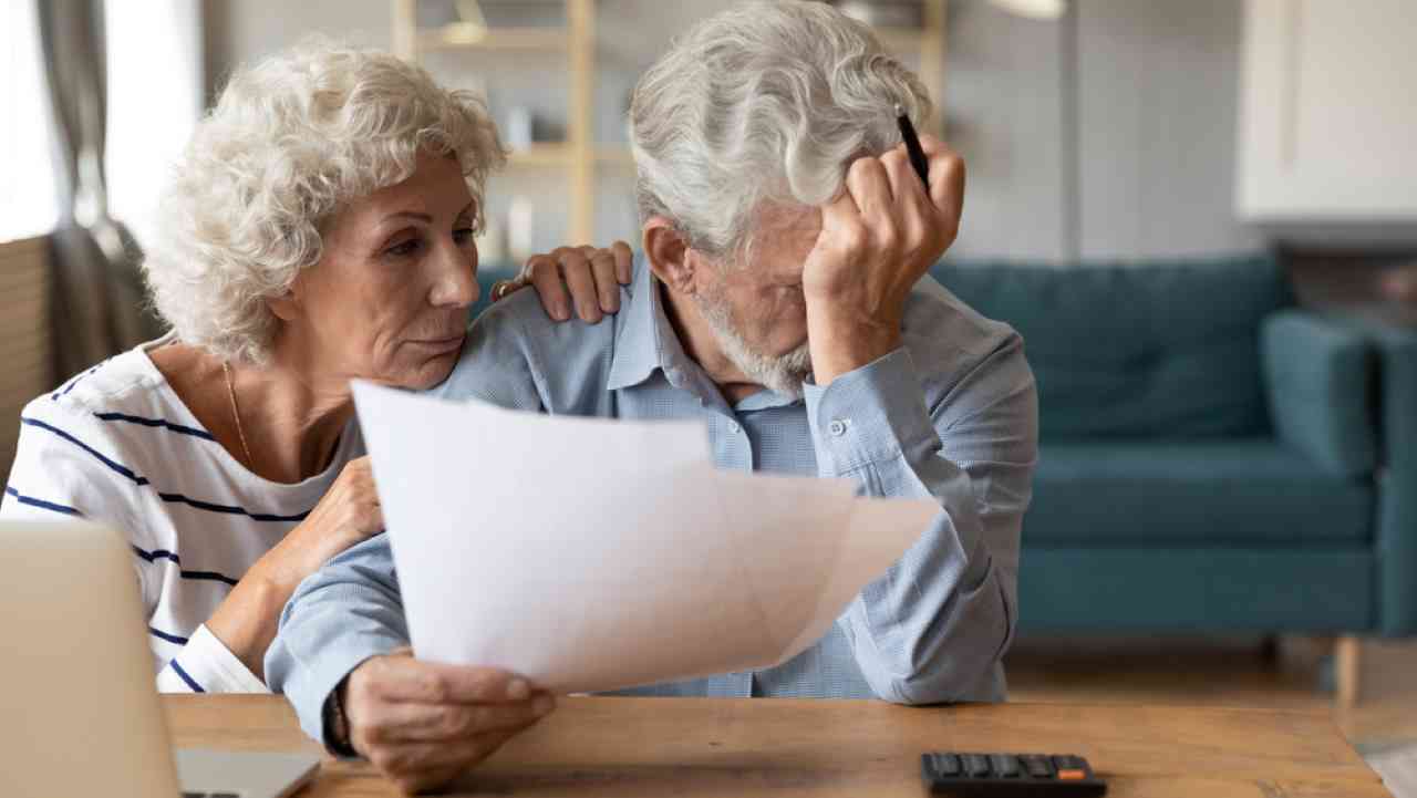 Casal de idosos aposentados conferindo as contas com expressão de preocupação