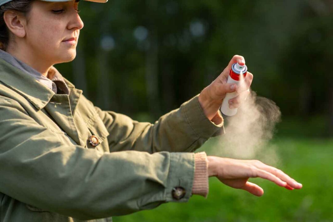 Mulher passando repelente em spray na mão