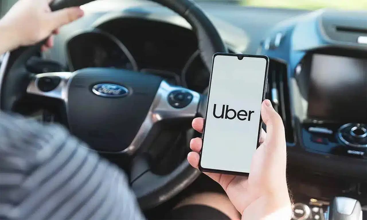 Motorista do aplicativo Uber dentro do carro segurando o celular