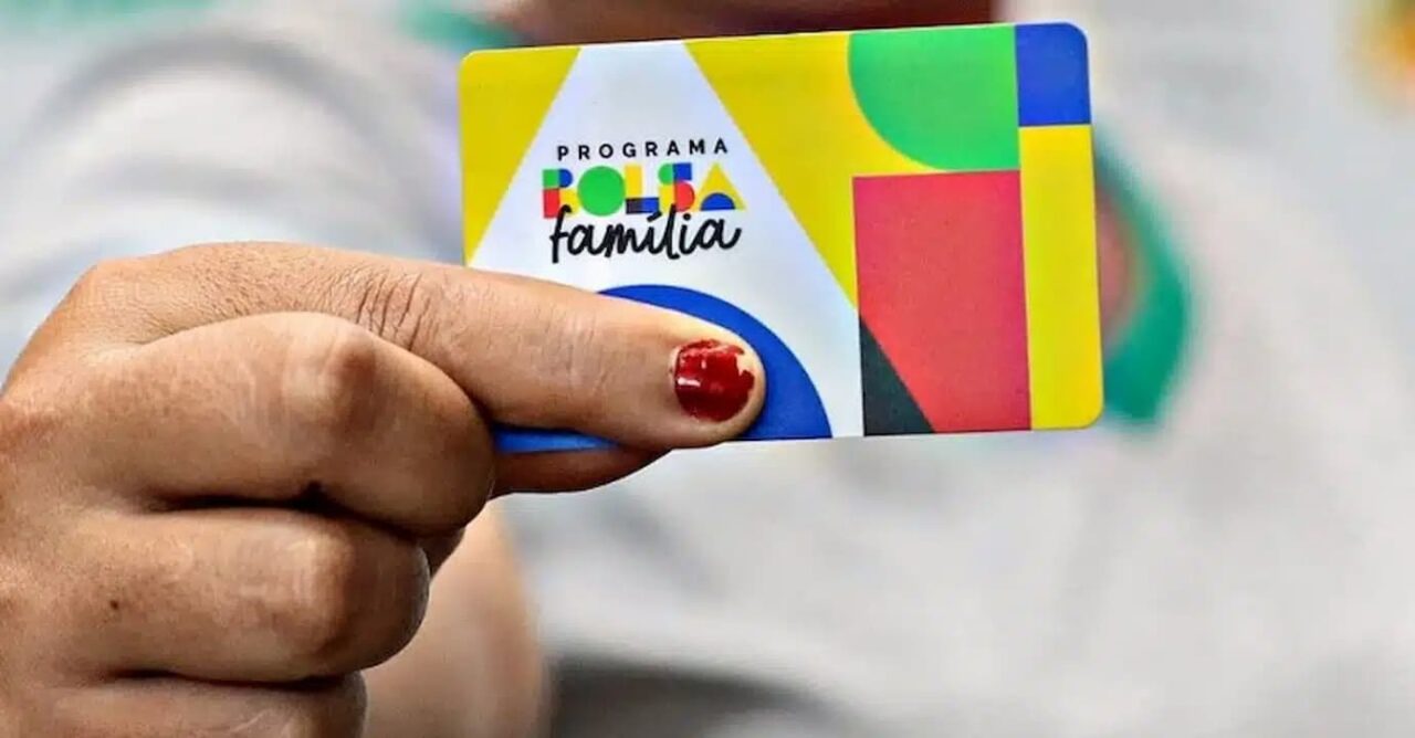 Mão feminina segurando cartão do Bolsa Família