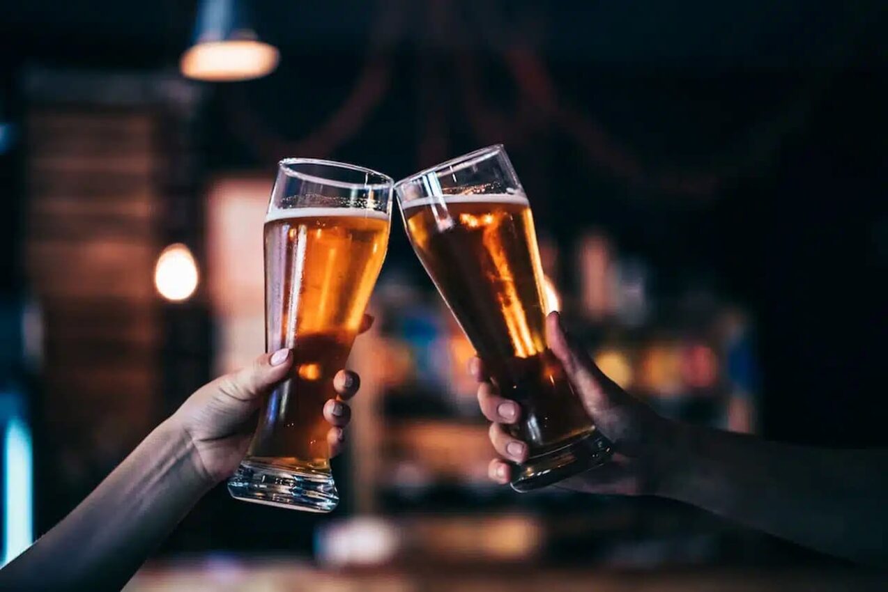 Imagem de duas pessoas brindando com copos de cerveja