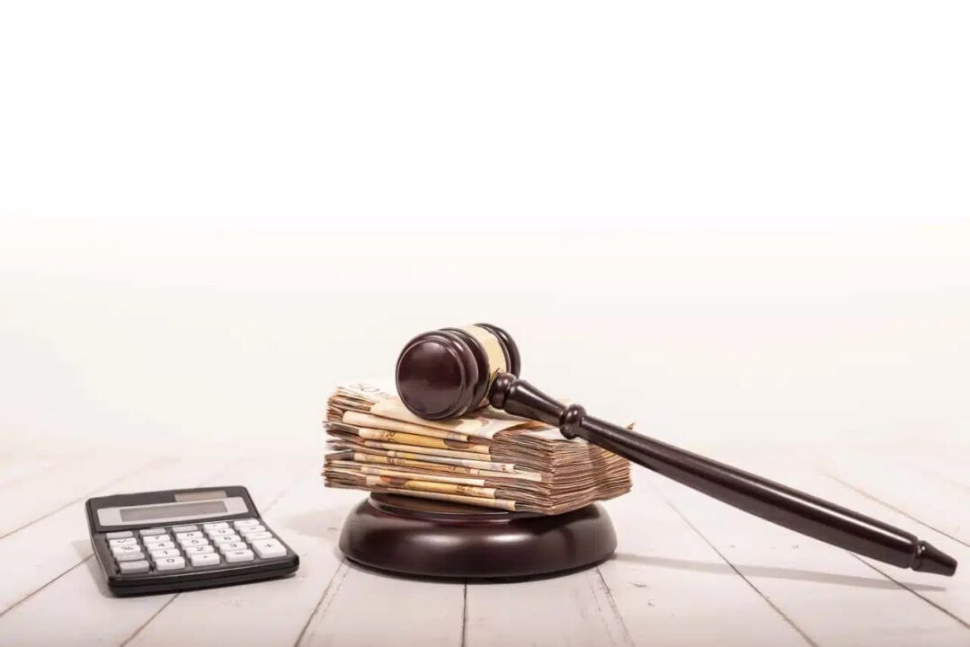 Calculadora, notas de dinheiro e martelo da justiça
