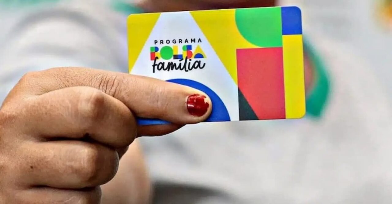 Mão feminina segurando cartão do Bolsa Família