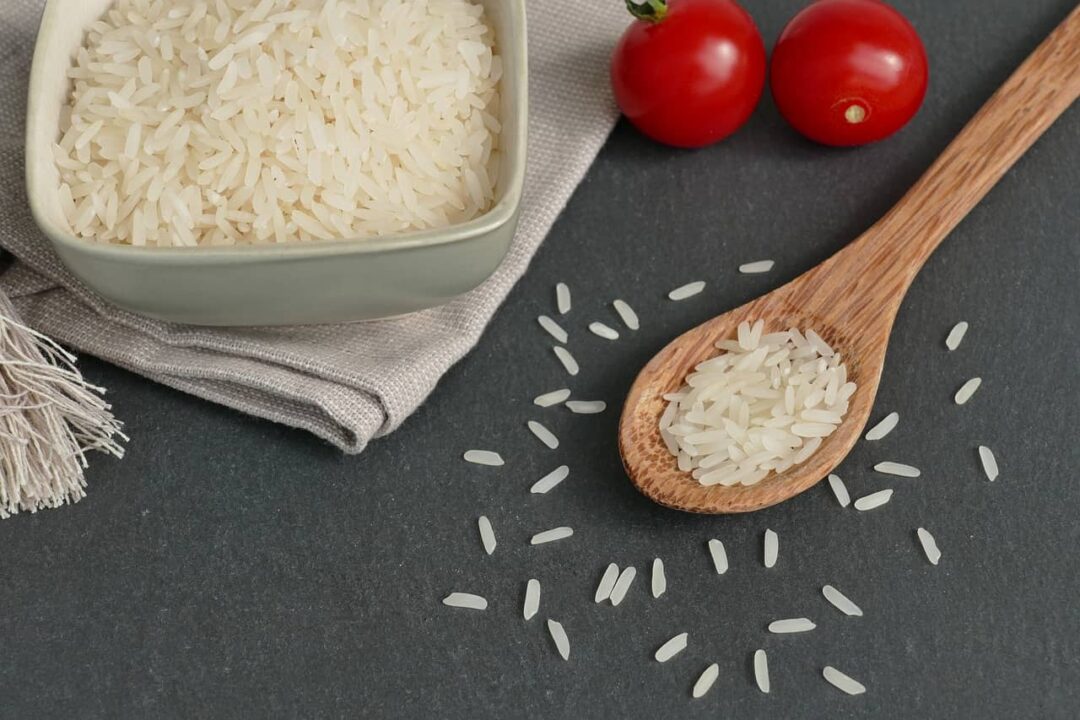 Imagem de uma tigela com arroz e ao lado uma colher de pau