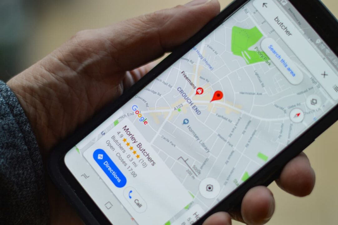Uma mão segurando um celular com o mapa marcando uma localização