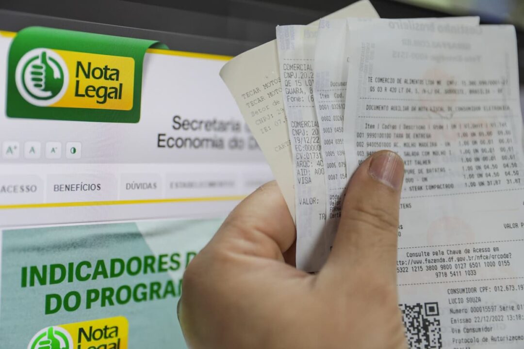 Uma mão segurando várias notais fiscais