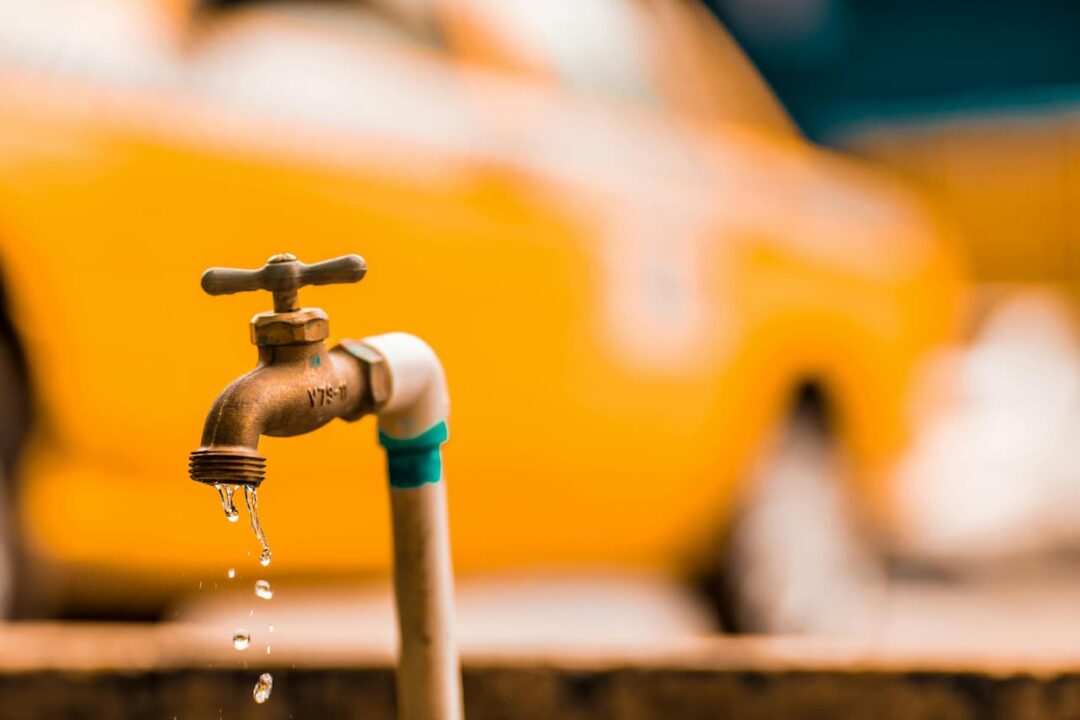 Uma torneira aberta com um carro amarelo no fundo